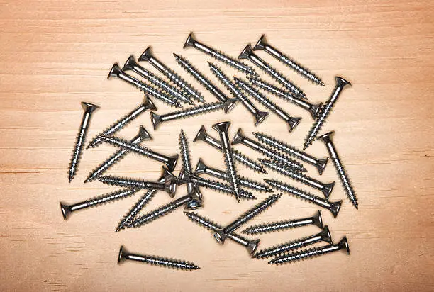 pile of wood screws on yellow pine board