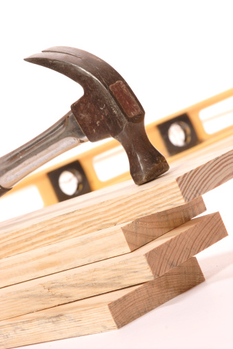 Hammer resting on One by Four wood strips with shallow depth of field. Level in background is out of focus to put emphasis on hammer and wood. Part of a construction theme.