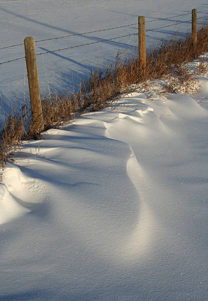 neve acumulada pelo vento ao longo da prairie cercas - prairie farm winter snow - fotografias e filmes do acervo