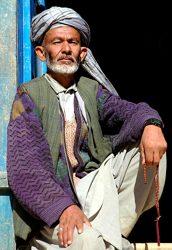 Syadara (Siyah Darah), Bamyan (Bamiyan) Province / Afghanistan: An Afghan man sits in a doorway in the small town of Syadara in Central Afghanistan. Man with turban and string of beads.