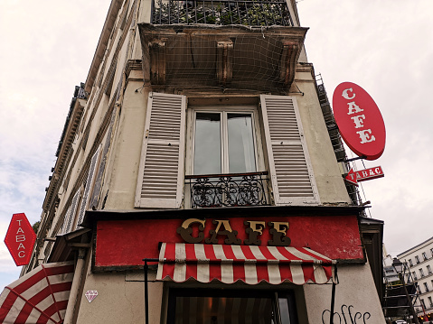 Paris, France. October, 2022. A tenement house in Paris with a cafe and a window with shutters.