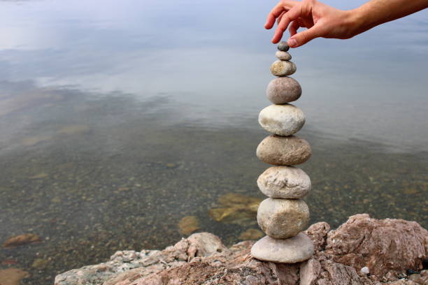istock A hand constructs equilibrium on pebbles. Perfect balance of stack of pebbles on the seashore. Concept of balance, harmony and meditation. Helping or supporting someone for growing or going higher. 1449583895