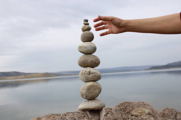 istock A hand constructs equilibrium on pebbles. Perfect balance of stack of pebbles on the seashore. Concept of balance, harmony and meditation. Helping or supporting someone for growing or going higher. 1449583911
