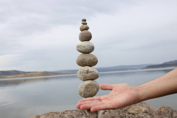 istock A hand constructs equilibrium on pebbles. Perfect balance of stack of pebbles on the seashore. Concept of balance, harmony and meditation. Helping or supporting someone for growing or going higher. 1449583928
