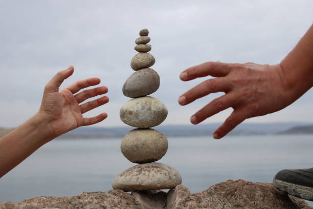 istock A hand constructs equilibrium on pebbles. Perfect balance of stack of pebbles on the seashore. Concept of balance, harmony and meditation. Helping or supporting someone for growing or going higher. 1449583995