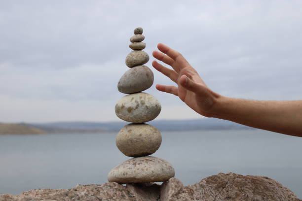 istock A hand constructs equilibrium on pebbles. Perfect balance of stack of pebbles on the seashore. Concept of balance, harmony and meditation. Helping or supporting someone for growing or going higher. 1449585132