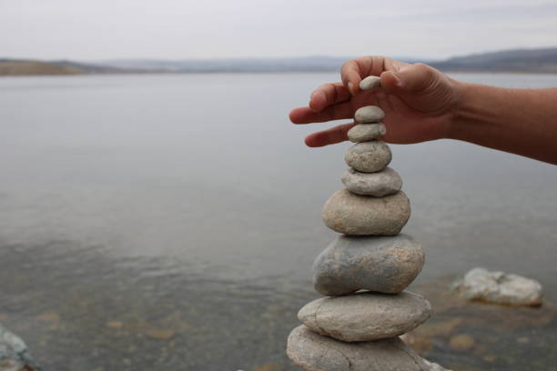 istock A hand constructs equilibrium on pebbles. Perfect balance of stack of pebbles on the seashore. Concept of balance, harmony and meditation. Helping or supporting someone for growing or going higher. 1449585166