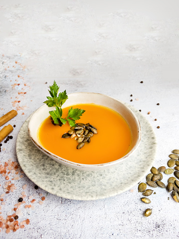 Pumpkin traditional soup with creamy  texture on gray textured background . Top view