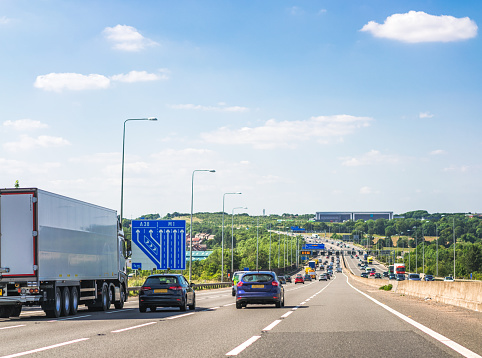 Busy daytime traffic as the M1 Motorway stretches into the distance in the English Midlands, on a sunny day in July.