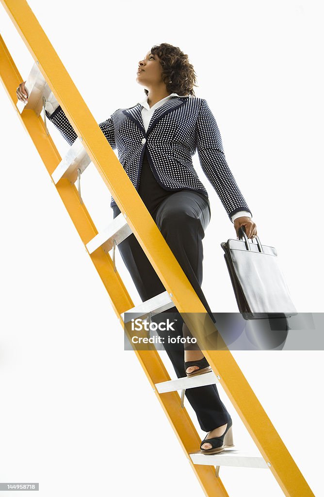 Businesswoman climbing ladder. African-American businesswoman holding briefcase and climbing yellow ladder. Climbing Stock Photo