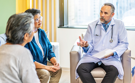 Group of senior people listening to male doctor. The doctor is describing the patient's condition with a data file in the hospital, Elder care, medicare services for older concept