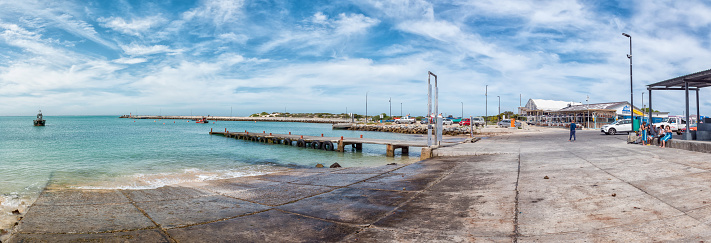 Struisbaai, South Africa - Sep 21, 2022: Panorama view of the harbor in Struisbaai, in the Western Cape Province. People, boats, vehicles and the waterfront are visible