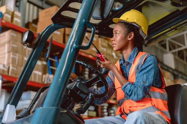 istock African black woman cargo worker work in warehouse working staff forklift driver command loading with ham radio. 1449589328