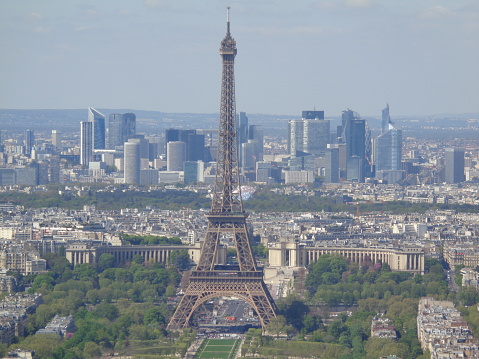 A vintage looking skyline photo taken in Paris France. The Eiffel Tower is to the right of the frame with dramatic clouds in the sky as a background.