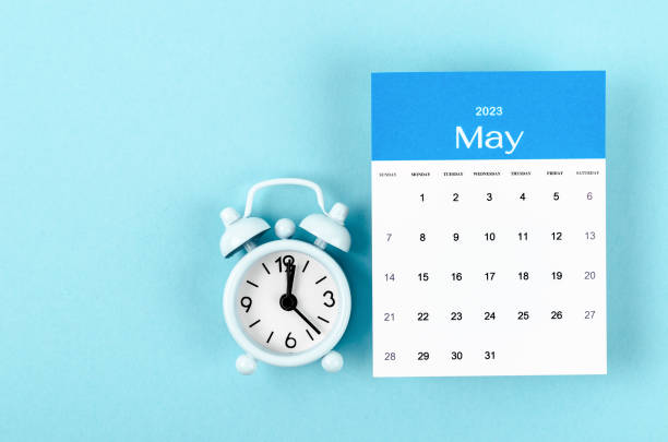 The May 2023 Monthly calendar for 2023 year with vintage alarm clock on blue background. stock photo
