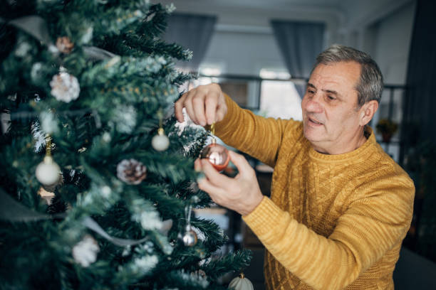 istock A happy man puts Christmas decorations on his tree 1449594383