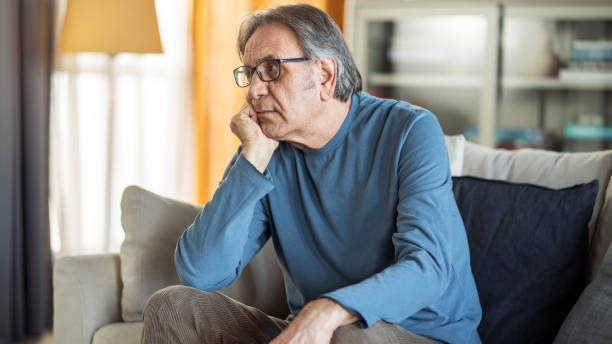 istock Old unhappy man sitting alone at home 1449594787