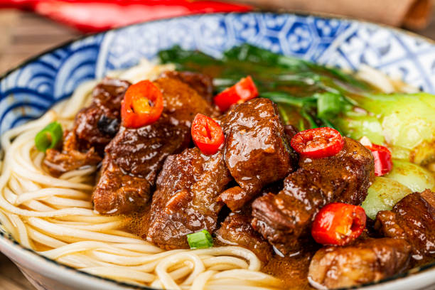istock Spicy red soup beef noodle in a bowl on wooden table 1449597972