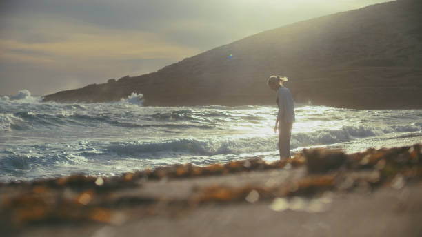 istock Woman walking alone on a coastside cliffs. Looking off into distant sea enjoying the wind 1449600037