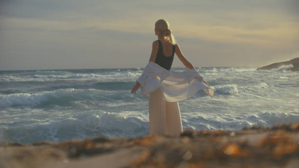 istock Woman standing alone on a beachside cliffs. Looking off into distant sea 1449600080