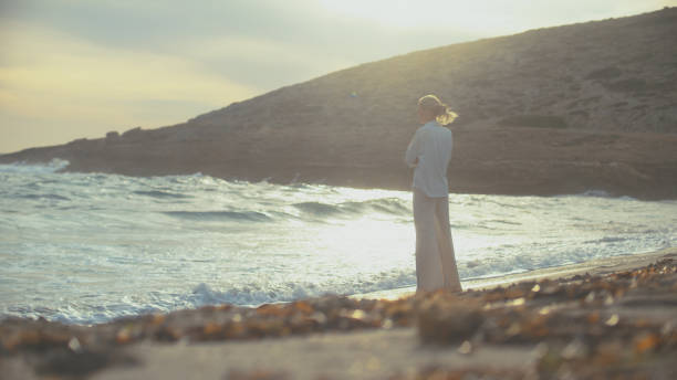 istock Woman walking alone on a beachside cliffs. Looking off into distant sea enjoying the wind 1449600090