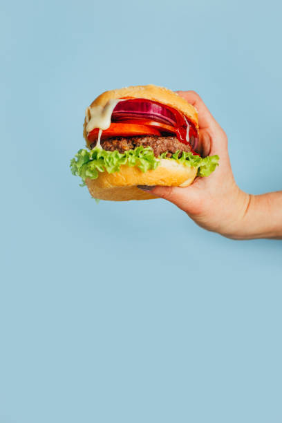 istock close-up on a hamburger in a female hand on a blue background 1449601952