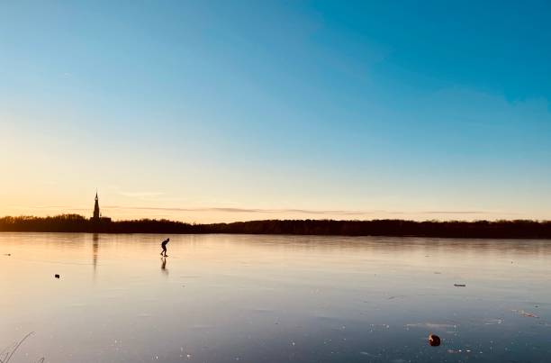 istock Frozen lake in the Netherlands with ice skaters at sunset 1449603778