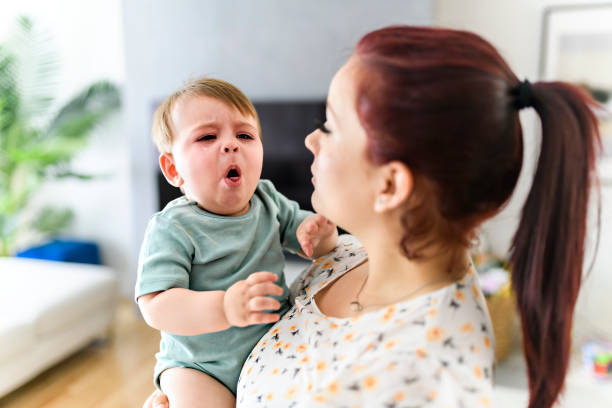 madre sosteniendo al bebé en la sala de estar. el bebé está enfermo con algo de tos - tosiendo fotografías e imágenes de stock