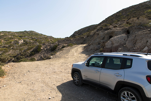 Vacation with a rental car. 4x4 SUV Jeep Renegade on dirt road on Rhodes island, Greece.