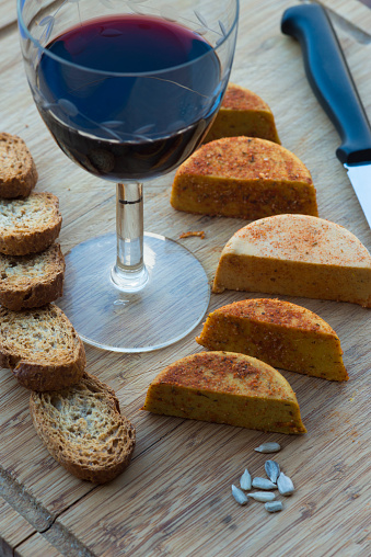 Vegan cheeses on a wooden table, accompanied by toasted bread and red wine.