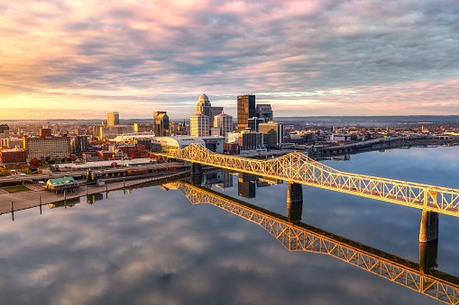 An aerial shot of the skyline of Louisville and the bridge at sunrise.