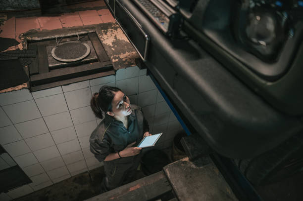 directly below Asian Chinese female mechanic checking car undercarriage in auto repair shop Asian Chinese female mechanic checking car undercarriage in auto repair shop car mechanic top view stock pictures, royalty-free photos & images