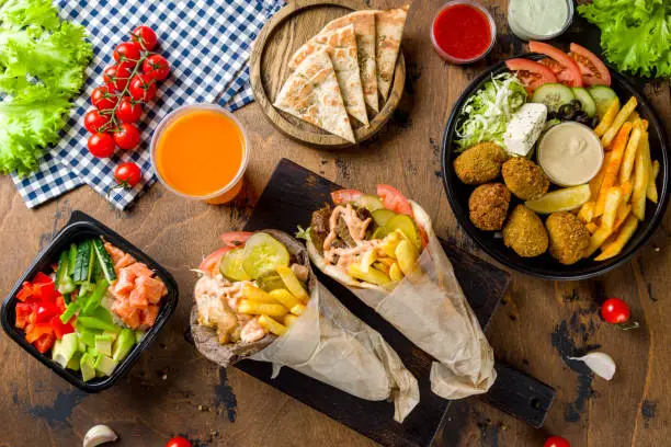 Gyros with chicken Greek cuisine, falafel, pita and poke with salmon on wooden table top view