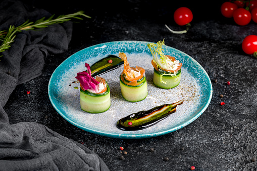 salmon rolls with cheese and cucumber on black table