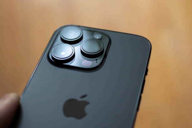Hamburg, Germany - December 15. 2022: Studio shot of a black handheld iPhone 14 Pro with focus on the three camera lens system against a brown background, in Hamburg,  Germany