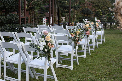 white wooden chairs with flower on a green lawn.