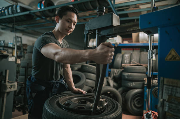 아시아 중국인 남성 정비사가 자동차 수리점에서 �기계로 타이어를 교체하고 있습니다. - hard labor 뉴스 사진 이미지