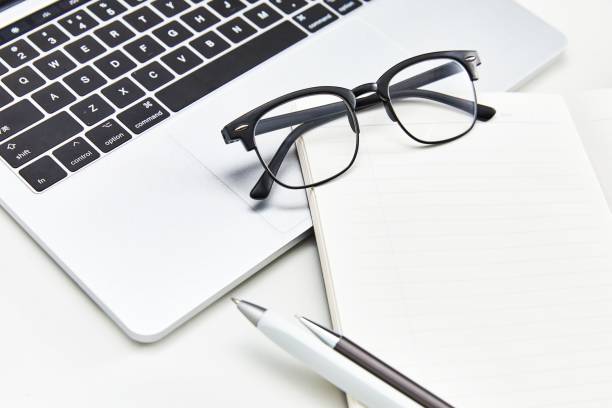 istock Office desktop with laptop, glasses, notebook and pens 1449619827