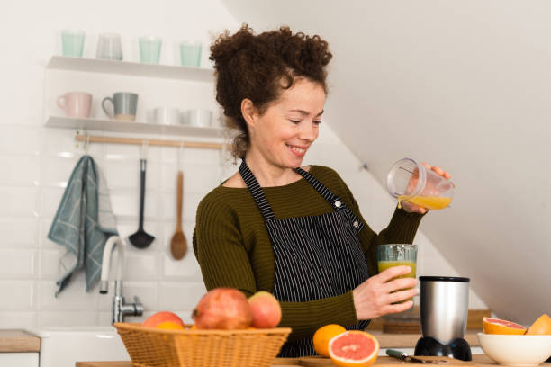 istock Happy young woman pouring just made fresh fruit juice 1449619937