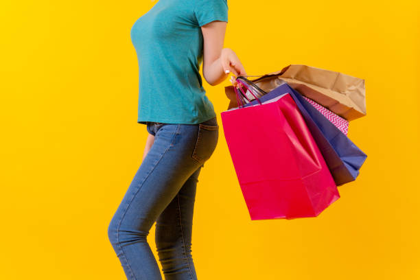 istock Unrecognizable person with colored shopping bags on discounts, yellow background studio 1449620522