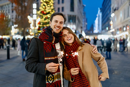 Couple holding sparklers while walking in the city at Christmas time