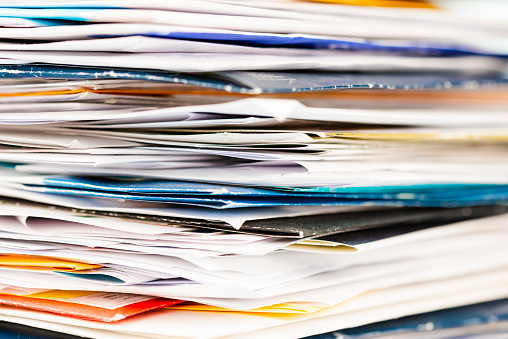 Large stack of junk mail or paperwork on a desk