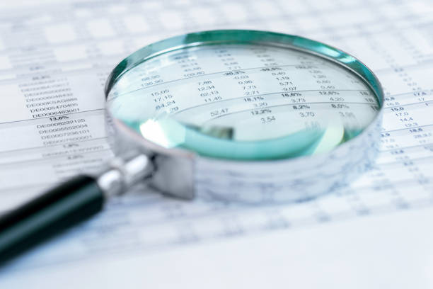 Magnifying glass lies on a document with numbers rows stock photo