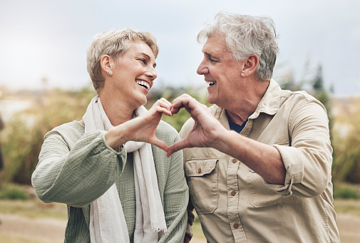 Love, heart sign and senior couple with marriage happiness, healthy and wellness lifestyle in countryside. Elderly people man, and woman with affection hands in park or nature retirement holiday