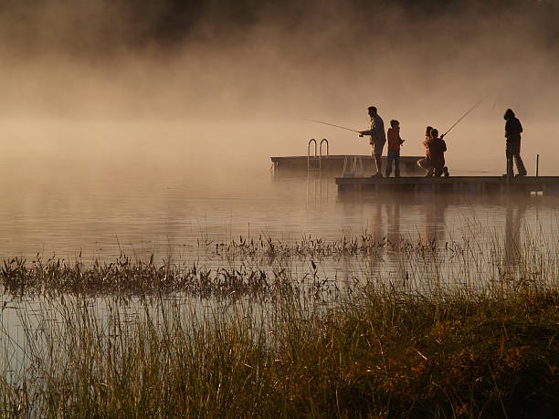 rodzina ryby na cichej mglisty lake od świtu. - fishing rod fishing fishing reel casting zdjęcia i obrazy z banku zdjęć
