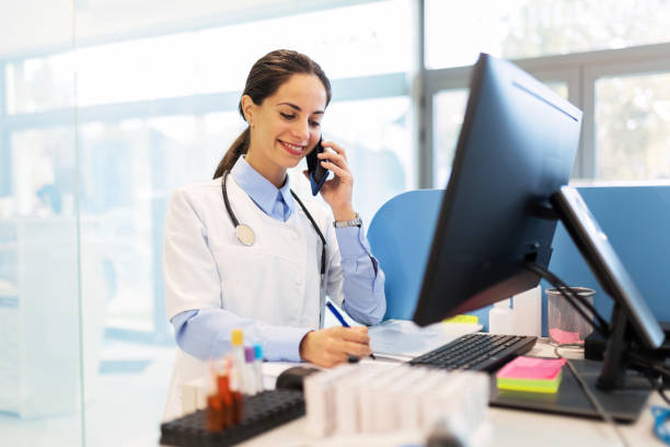 istock Smiling female scientist in laboratory using smart phone 1449628836