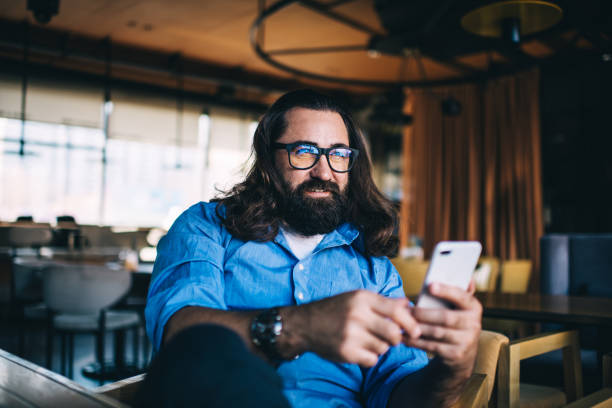 istock Smiling male surfing mobile phone in creative cafe 1449630861