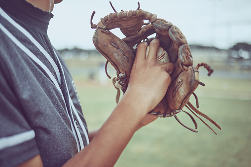 Baseball player, hands or ball in mitt on grass field for fitness, workout and training in game, match and competition. Zoom, baseball glove and sports athlete in energy exercise for softball pitcher