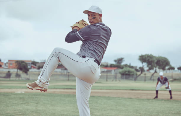 baseball, sport e uomo che lancia una palla durante una partita professionale su un campo con una squadra. lancio dell'atleta durante un evento per sport, competizione o allenamento con concentrazione, equilibrio e velocità in un parco - pitcher di baseball foto e immagini stock