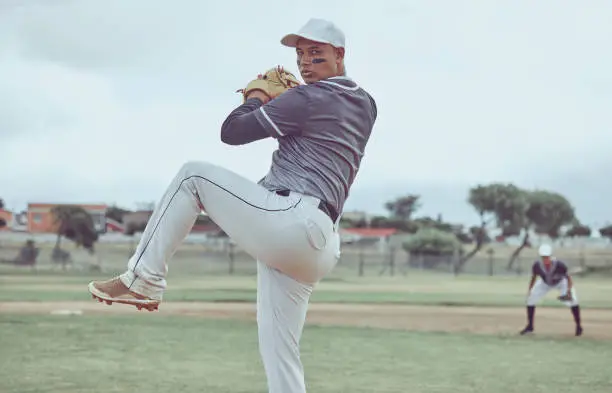 Baseball, sports and man throwing a ball during a professional game on a field with a team. Athlete pitching during an event for sport, competition or training with focus, balance and speed at a park